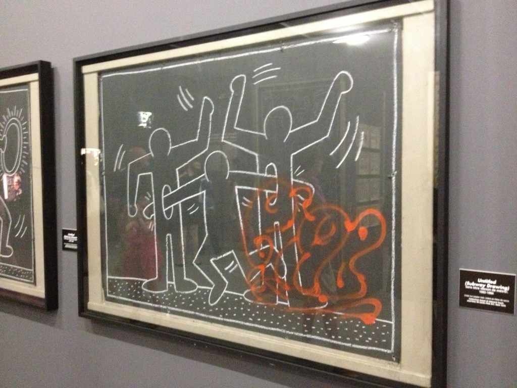 Sans Titre, Dessin à la craie blanche sur une feuille de papier noir, dans le métro new-yorkais. Le dessin a été graffité à la bombe orange avant d’être récupéré par un collectionneur. (Cliché L. Kloeckner, 2013)