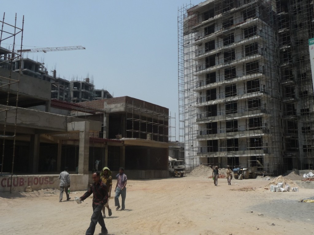 Ouvriers sur un chantier de la DMRC. Le dépôt du métro est souterrain et les condominiums et leurs équipements (piscine, club house, court de tennis) sont bâtis en surface (Bon, 2013)